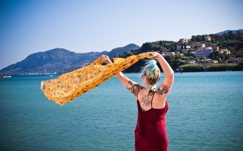 woman waving yellow textile near body of water during daytime