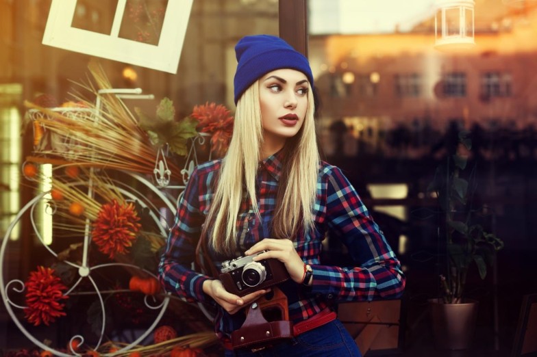 Fashionable blonde woman wearing beanie and flannel holding a camera