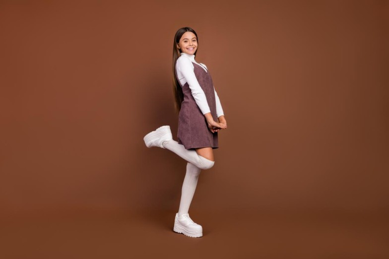 Young woman posing with a dress and platform shoes in brown background
