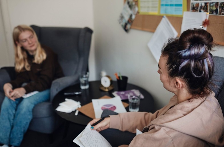 Mental health professional discussing with female student in school office