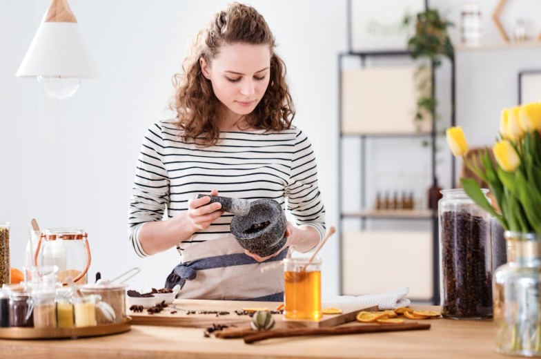 Passionate girl grinding herbs to produce organic cosmetics