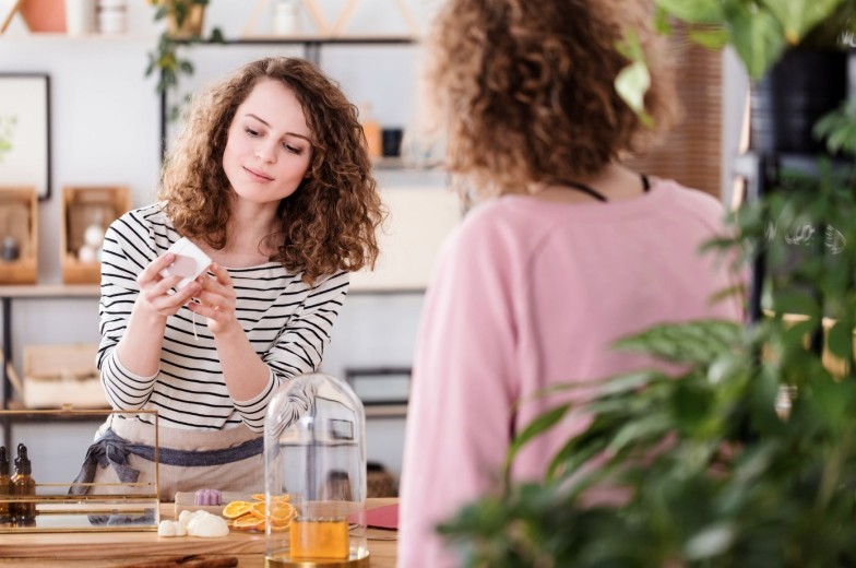Woman selling organic skincare products in a small, local shop