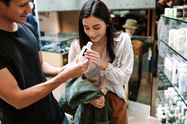Female customer smelling beauty product in store and smiling
