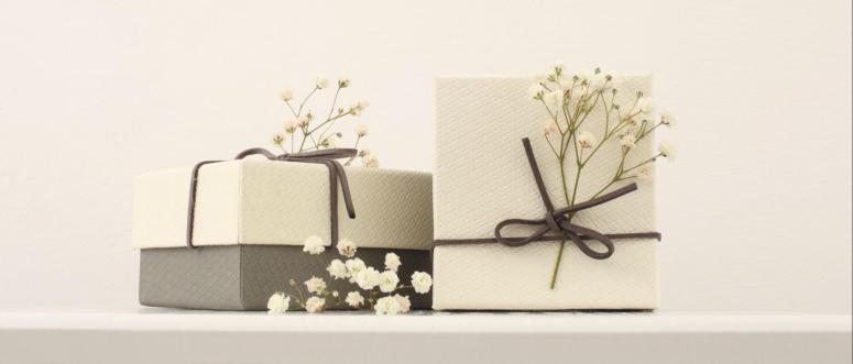 Craft gift boxes with flower on light beige wall background Copy space for text message