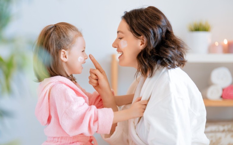 A happy family! Mother and daughter girl take care of the skin in the bathroom