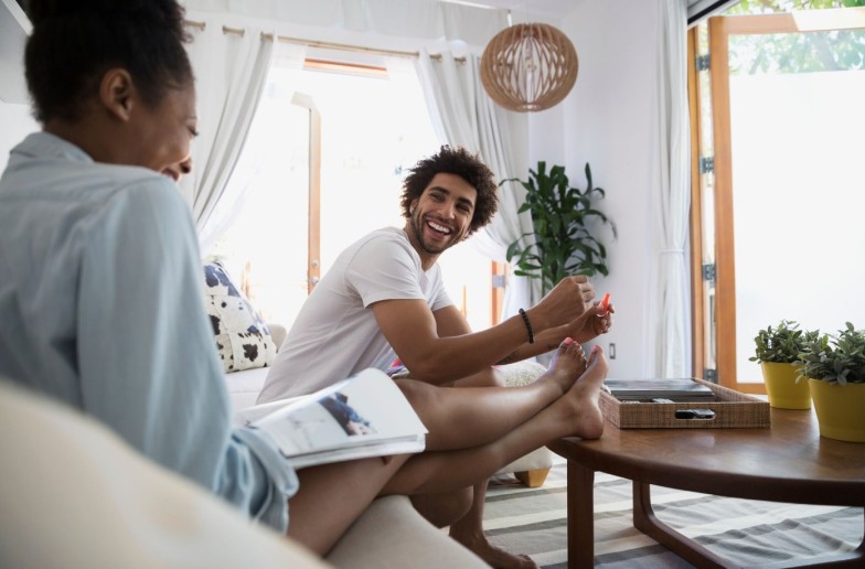 Man giving girlfriend pedicure in living room