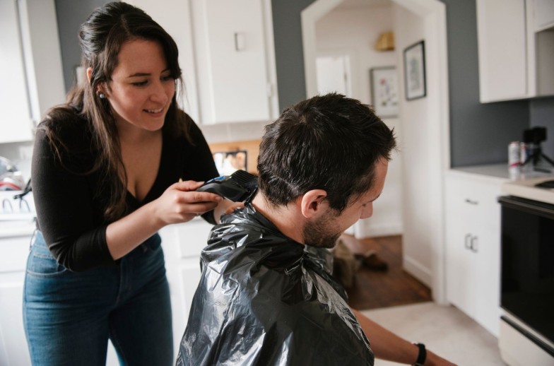 Woman cutting man's hair with clippers