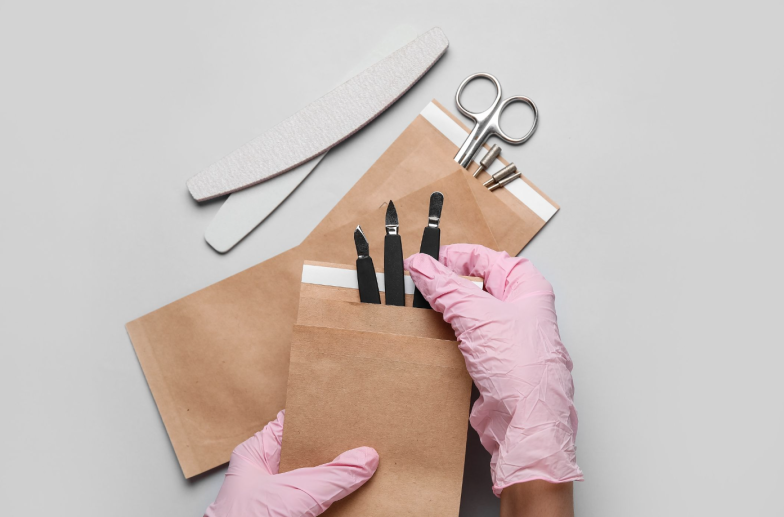 Female hands with manicure equipment on light background