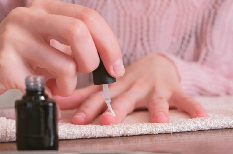 Woman puts primer on her nails before putting shellac. Close-up hands