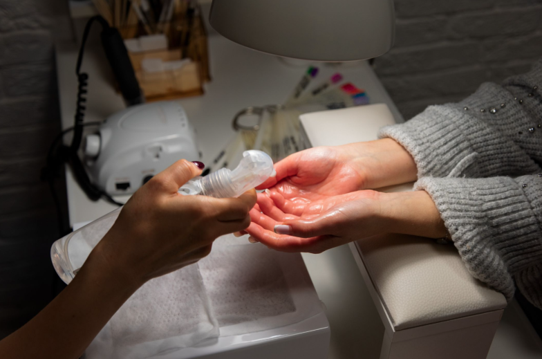 manicurist treats client's hands with antiseptic