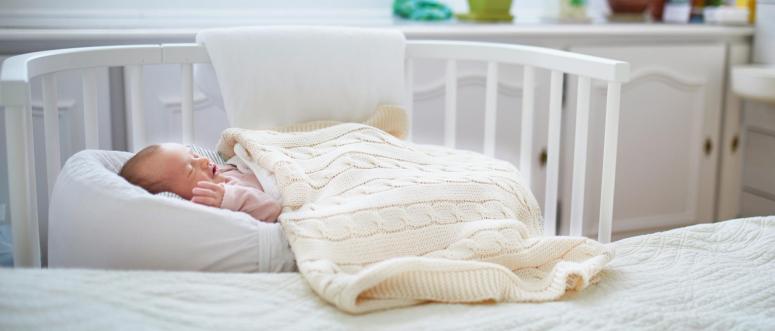 Newborn baby girl having a nap in co-sleeper crib attached to parents bed Newborn baby girl having a nap in co-sleeper crib attached to parents bed