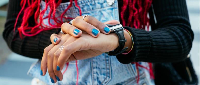 From above of crop anonymous black female wearing rings on manicured fingers with blue nail polish touching wristwatch From above of crop anonymous black female wearing rings on manicured fingers with blue nail polish touching wristwatch