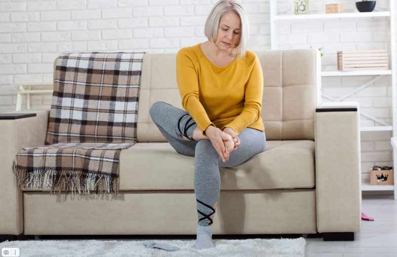 Middle-aged woman suffering from pain in leg at home, closeup
