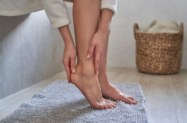 Caucasian woman in bathrobe applying moisturizing cream on heels