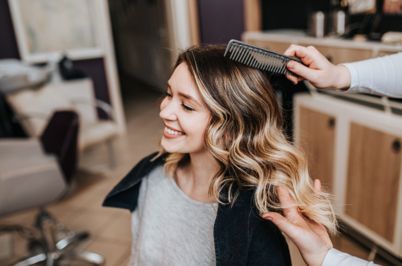 Beautiful hairstyle of young woman after dyeing hair and making highlights in hair salon.