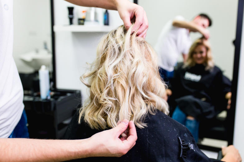 Beautiful hairstyle of young woman after dying hair and making highlights in hair salon.