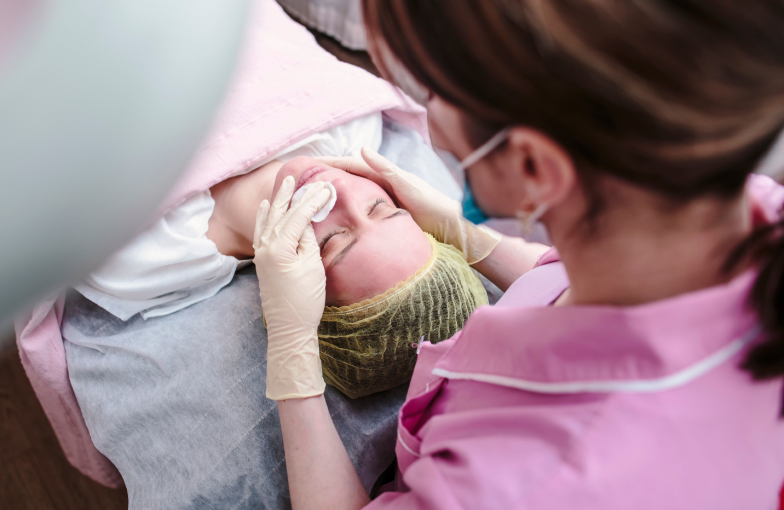 Doctor - cosmetologist prepares the skin of the patient's face for chemical peeling.
