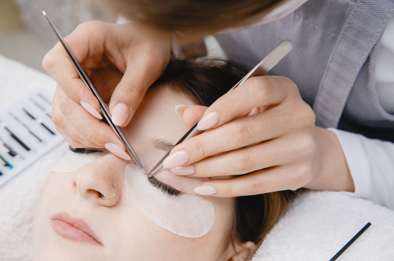 Eyelash extension procedure. Master tweezers fake long lashes beautiful woman eyes.