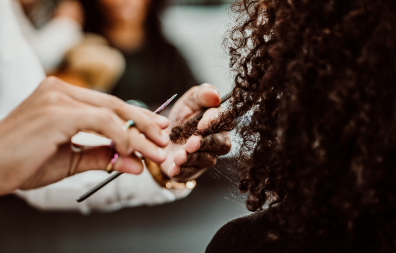 Beautiful latin woman with short curly brown hair getting a treat at the hairdresser. Latin hairdresser working her afro hair. Lifestyle.Close up