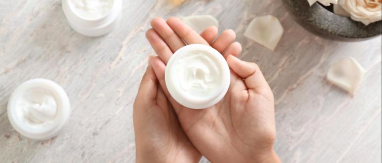 Woman holding jar with body cream over light table Woman holding jar with body cream over light table