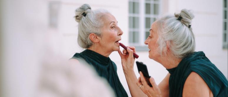 Senior women twins in city walk completing make-up with lipstick Senior women twins in city walk completing make-up with lipstick
