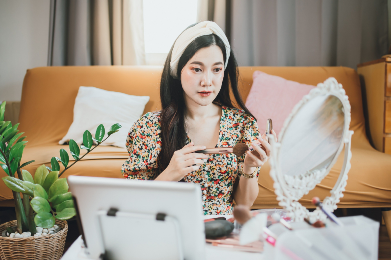 A beautiful Asian woman using a tablet for self makeup learning online at home during the Covid-19 (Coronavirus) outbreak. Home learning concept.