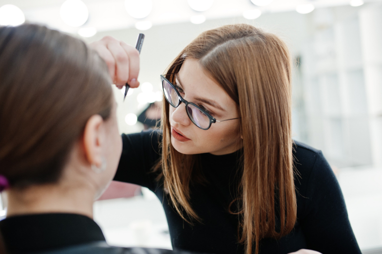 Make up artist work in her beauty visage studio salon. Woman applying by professional make up master. Beauty club concept.