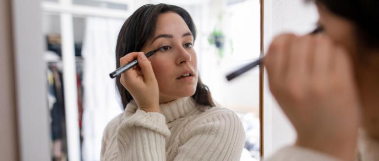 Woman doing makeup in mirror Woman doing makeup in mirror