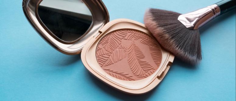 Texture Bronzer and makeup brush on a blue background closeup Texture Bronzer and makeup brush on a blue background closeup