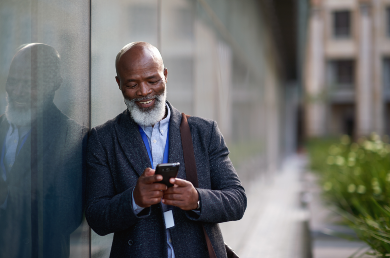Mature african american businessman using smartphone in city texting on mobile phone