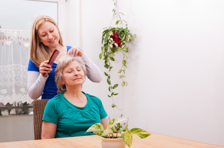 blond young woman combing seniors hair