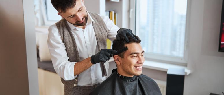 Waist up portrait of stylishly dressed barber prepares the handsome Indian client for a haircut Waist up portrait of stylishly dressed barber prepares the handsome Indian client for a haircut