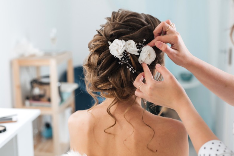 Your wedding day is a celebration of love, and your hair should be as special as the occasion. Discover the magic of beautiful wedding hairstyles that will make you feel like the belle of the ball. Whether you're looking for a romantic updo, a boho braid, classic Hollywood waves, or an elegant low bun, we've got you covered.  Your hair is your crowning glory, and on your wedding day, you deserve a style that reflects your personality and enhances your bridal beauty. Let's dive into these stunning wedding hairstyles to find the perfect one for your dream day.  1. Romantic Updo Timeless and versatile, the romantic updo is a classic choice that fits a variety of wedding themes. It effortlessly combines elegance with a touch of modern romance.  Prep Your Hair: Start by prepping your hair with the right products to add texture and hold.  Create loose curls: Use a curling iron to create loose, cascading curls.  Gather into a low bun: Gather the curls into a low bun, leaving a few strands loose for a soft, romantic touch.  Secure and Finish: Secure the updo with pins and finish with a mist of hairspray for hold.  Styling Tips  Finish the look with delicate hair accessories for a touch of sparkle.  Consider face-framing tendrils for a softer, more whimsical look.  Your wedding day is all about timeless moments, and the romantic updo ensures you'll look back on your photos with delight.  2. Boho Braided Crown Embrace a carefree and bohemian vibe with the Boho Braided Crown. This ethereal style is perfect for outdoor or rustic weddings.  Center part: Part your hair down the middle to create two even sections.  Loose Braids: Create two loose braids on each side, making sure they are not too tight.  Create the crown: Cross the braids over your head and secure them in a crown shape with pins.  Loose strands: Allow a few loose strands to frame your face for an effortless finish.  Styling Tips  Incorporate flowers or greenery into the braids for a boho-chic touch.  Enhance the texture with a touch of sea salt spray for a relaxed, beachy feel.  The boho braid is not just a hairstyle; it's a statement that says, "I'm here to celebrate love in style.  3. Classic Hollywood Waves Step into the glamour of the silver screen with classic Hollywood waves. This sophisticated style is the epitome of timeless elegance, perfect for formal and black-tie weddings.  Voluminous waves: Use a large barrel curling iron to create voluminous waves that cascade gracefully.  Brush for softness: Brush through curls to create soft, flowing waves that evoke old Hollywood glamour.  Side part: Part the hair on the side for a classic Hollywood look.  Finishing Touch: Finish the look with a mist of hairspray to hold the waves in place.  Styling Tips  Opt for a deep side part to add an extra dose of drama to your bridal look.  Use a shiny serum for a shiny, polished finish.  Classic Hollywood waves aren't just a hairstyle; they're a nod to the timeless beauty of iconic movie stars.  4. Elegant low bun For a polished and sophisticated bridal look, the elegant low bun is a timeless choice that complements a variety of face shapes and bridal gown styles.  Gather into a low ponytail: Begin by gathering your hair into a low ponytail at the nape of your neck.  Twist into a bun: Twist the ponytail into a sleek bun and secure with pins.  Smooth flyaways: Use a small amount of styling cream to smooth any flyaways for a polished finish.  Set with hairspray: Finish the look with a mist of hairspray to ensure the bun stays in place throughout the party.  Styling Tips  Add elegance with a decorative hairpin or comb.  Keep the bun sleek for a modern and sophisticated aesthetic.  The elegant low bun is not just a hairstyle; it's a testament to the grace and sophistication that defines timeless beauty.  Bottom Line Your wedding day is a canvas, and your hair is the brushstroke that completes the masterpiece. Beautiful wedding hairstyles allow you to express your style, embrace romance, and celebrate love. From the romantic updo to the boho braid, and classic Hollywood waves to the elegant low bun, each style tells a unique story.  Choosing the perfect wedding hairstyle is a personal journey, and we hope this guide has inspired you to find the one that matches your bridal vision. Remember, your wedding day is about you, your love story, and the beginning of a beautiful adventure.  As you plan your wedding beauty journey, MobileStyles is here to connect you with talented beauty professionals who specialize in creating the perfect bridal look. Your dream wedding starts with a vision, and your vision comes to life with the right team of beauty professionals. Download the MobileStyles app today to discover the beauty professionals who will make your wedding day truly magical. Let's make every moment beautiful!