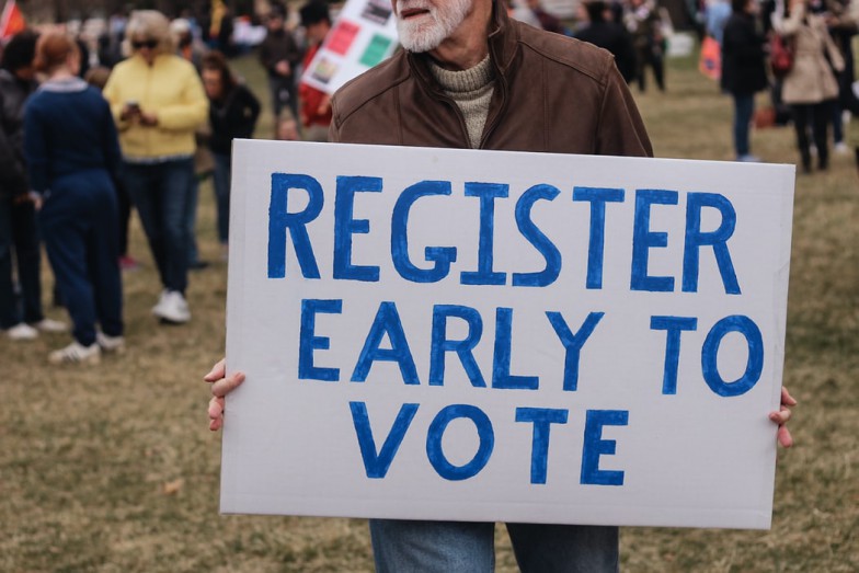person holding a register early to vote sign photo