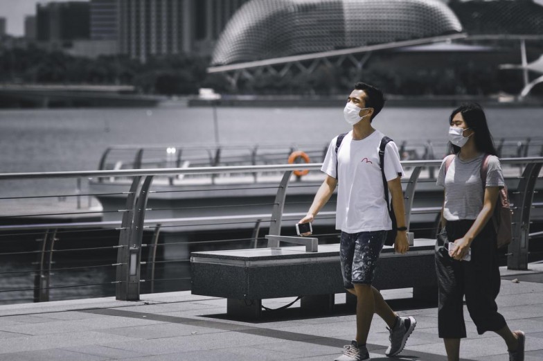 man in white t-shirt and black shorts standing on black bench during daytime photo