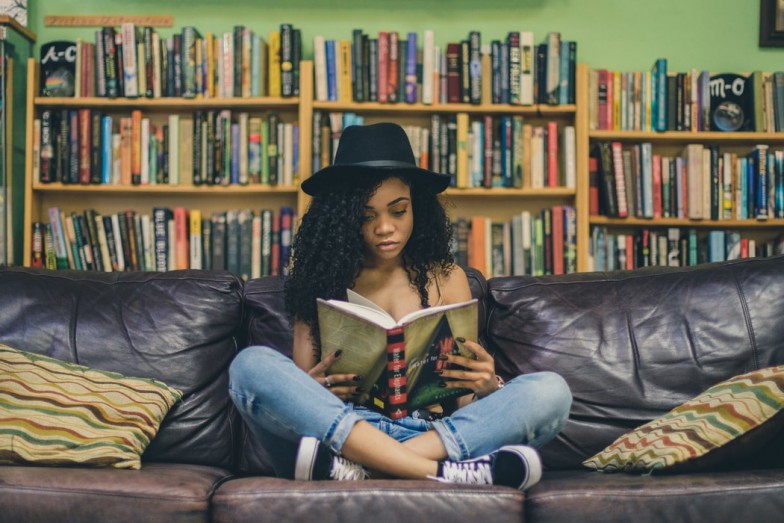 woman reading a book while sitting on black leather 3-seat couch photo